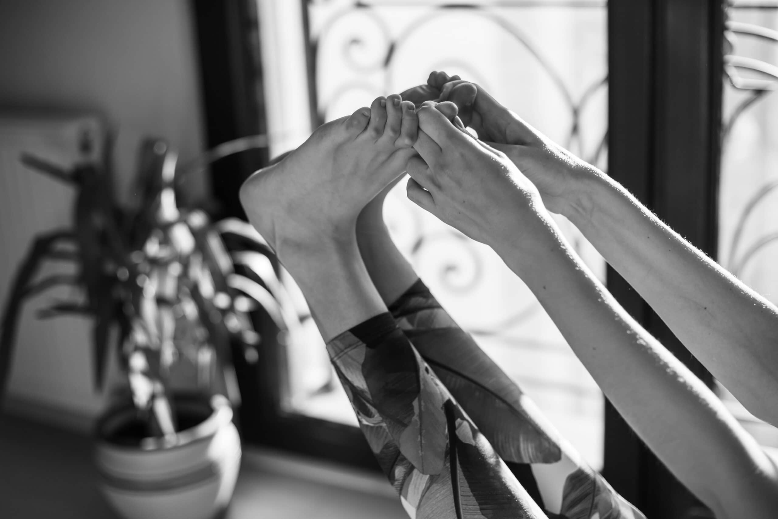 A woman is stretching her feet in front of a window to alleviate her plantar fasciitis.